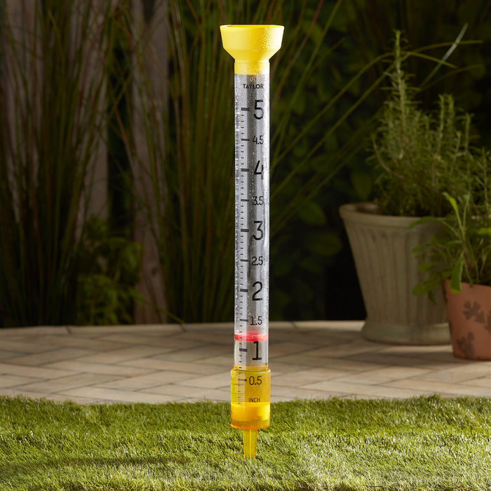 Jumbo Jr 5 inch rain gauge installed in a backyard with yellow funnel top and clear measurement tube.