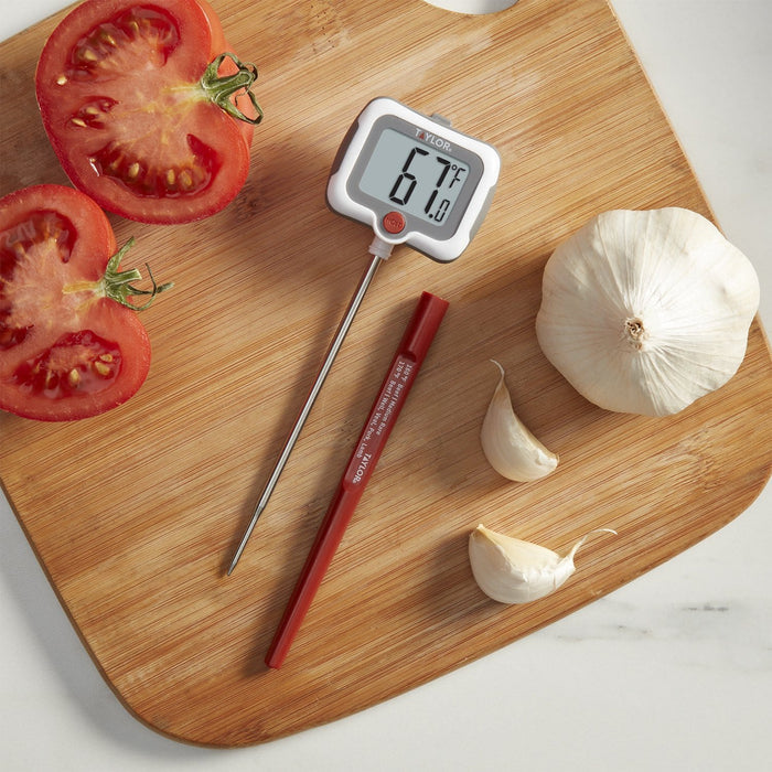 Pivoting display thermometer on a wooden cutting board beside sliced tomatoes and garlic.