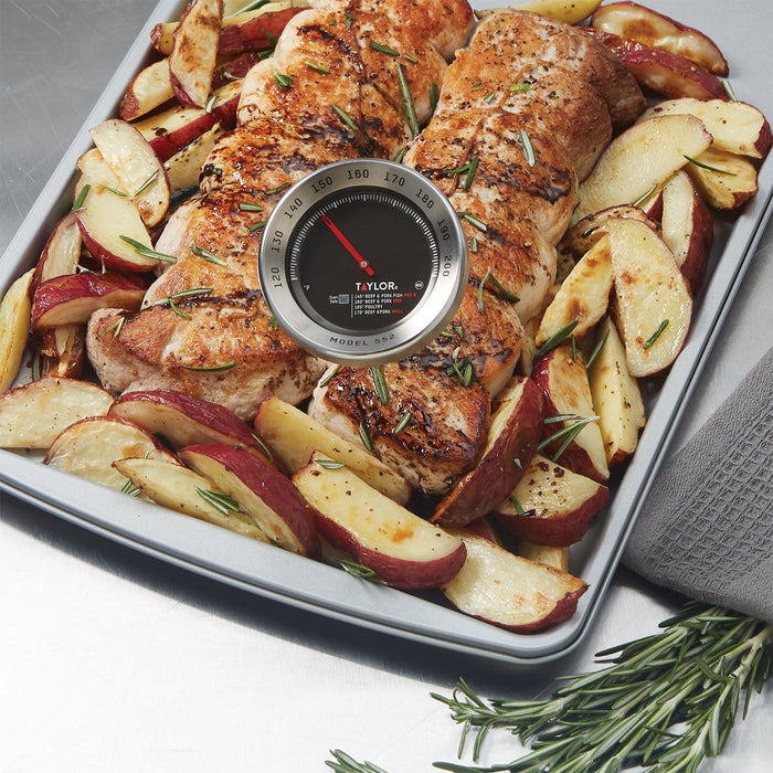 Roasted chicken and potatoes on a tray with a Taylor Model 552 leave in thermometer inserted in the meat