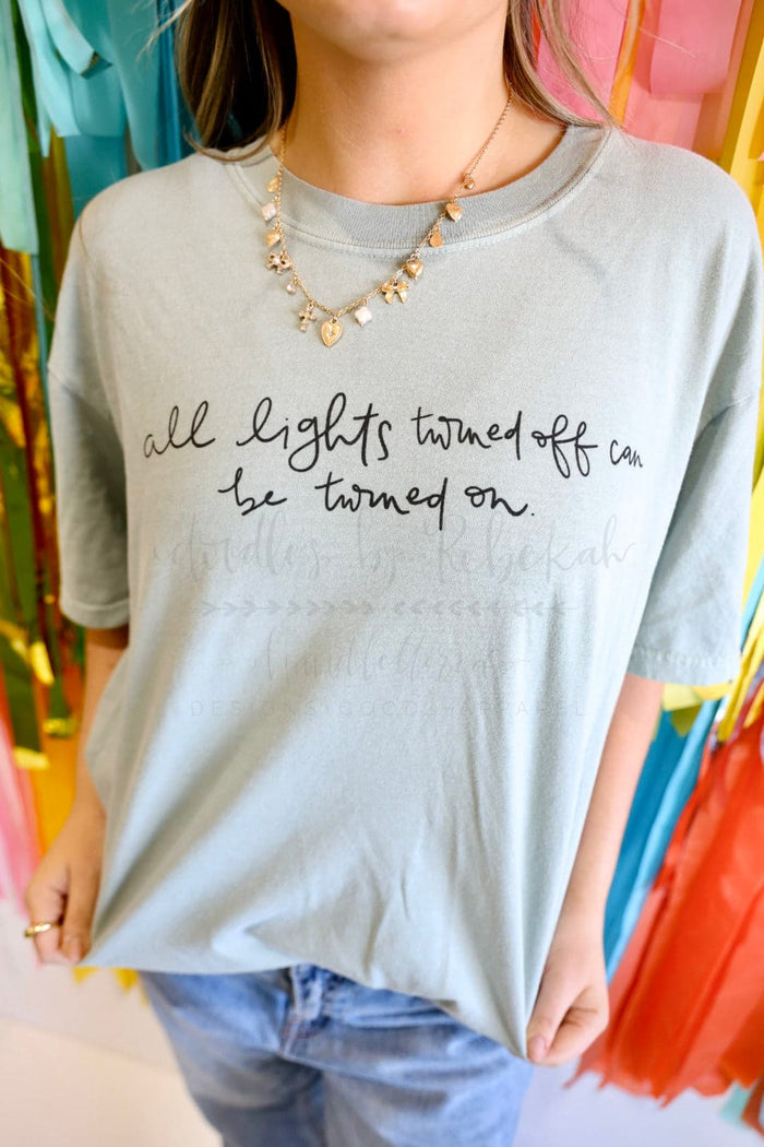 a woman showing off a light great t-shirt with the words "all lights turned off can be turned on"