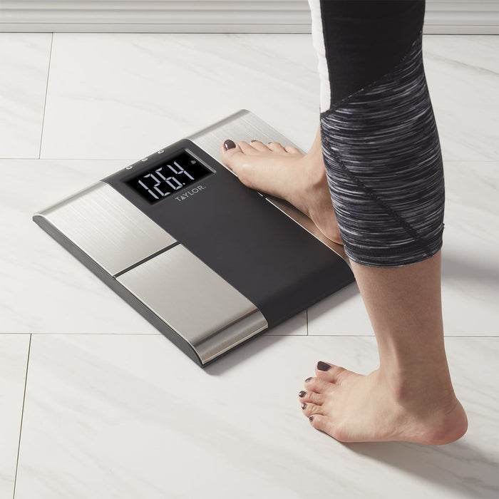 Foot on a sleek digital Body Composition Scale with a visible weight readout.