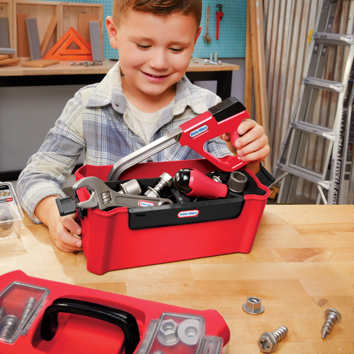 Child playing with a toy tool set on a wooden table