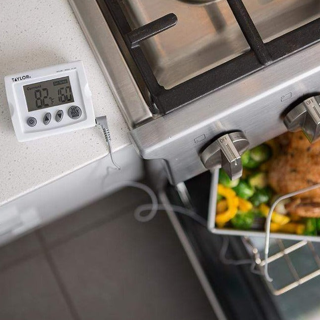 Digital probe thermometer with wall display next to a roasting pan in the oven