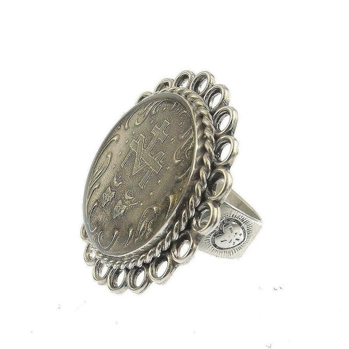 Silver ring featuring an antique coin, ornate detailing, and oval design.