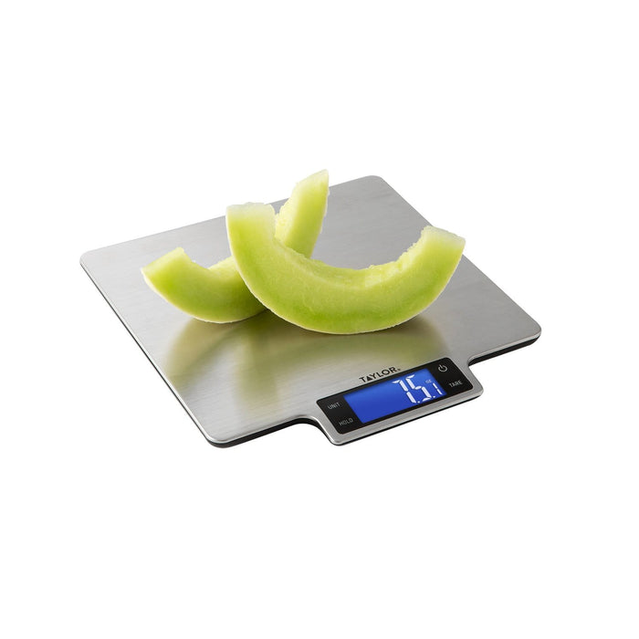 Cantaloupe slices on a large brushed stainless steel platform kitchen scale with a blue digital display.