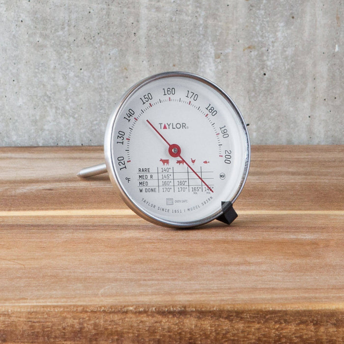 Taylor meat thermometer with a large round dial resting on a wooden surface