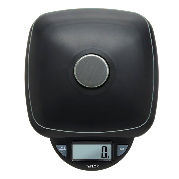 Close-up of a black digital kitchen scale showing a large brushed metal circular control on the top