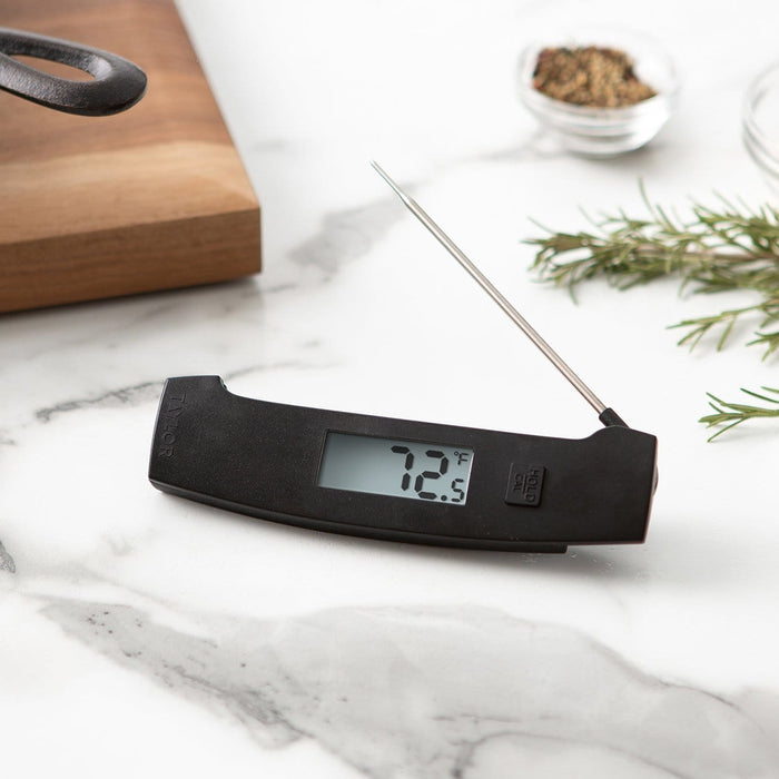 Hand holding the PRO Ultra-Fast Thermocouple to measure steak temperature in a skillet.