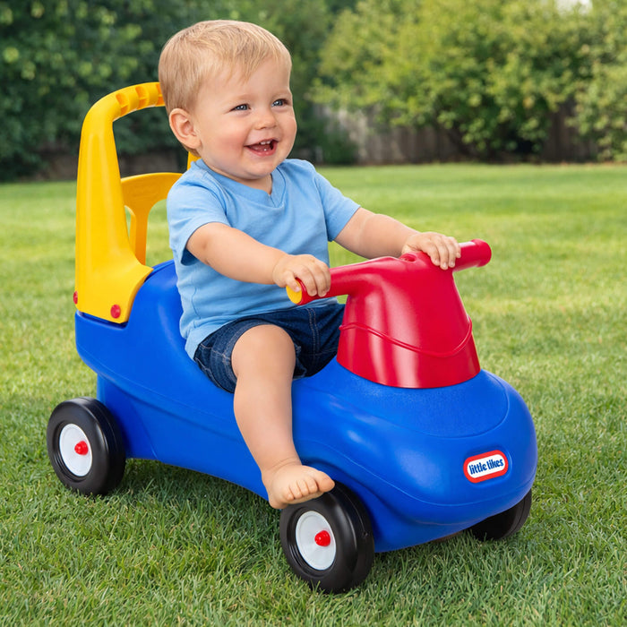 Child riding a colorful toy car on grass