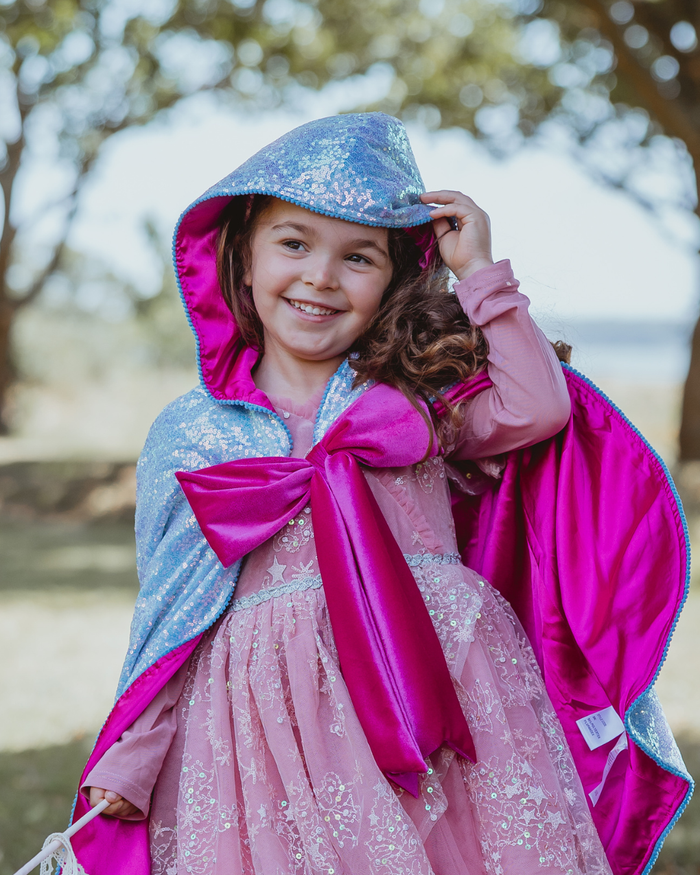 Child wearing a blue sequin hooded fairy godmother cape with a magenta lining