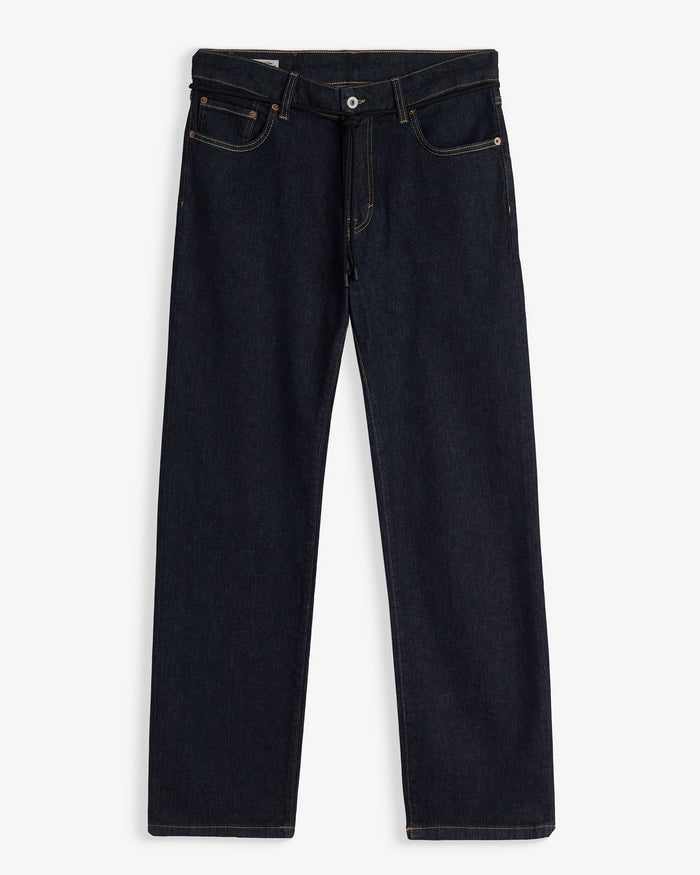 A front view of The Jeans Relaxed Straight Fit in Rinse Wash, laid flat on a white background. The image highlights the straight leg silhouette, zip fly with top button, front pockets, subtle orange accent stitching, and a black drawstring detail at the waist.