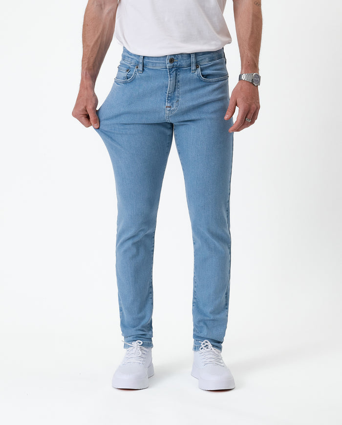 The Jeans Skinny Fit in light blue — stretching the fabric to show the flexible Motion Fabric