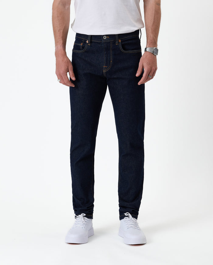 The Jeans Slim Fit in rinse wash — front view with white sneakers