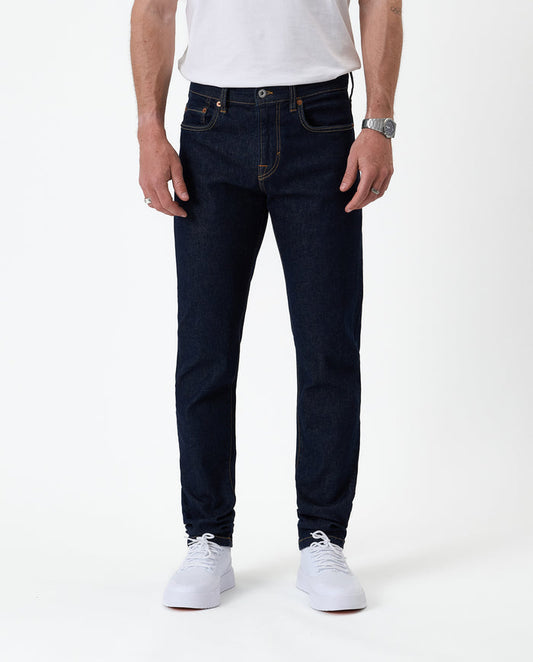 The Jeans Slim Fit in rinse wash — front view with white sneakers