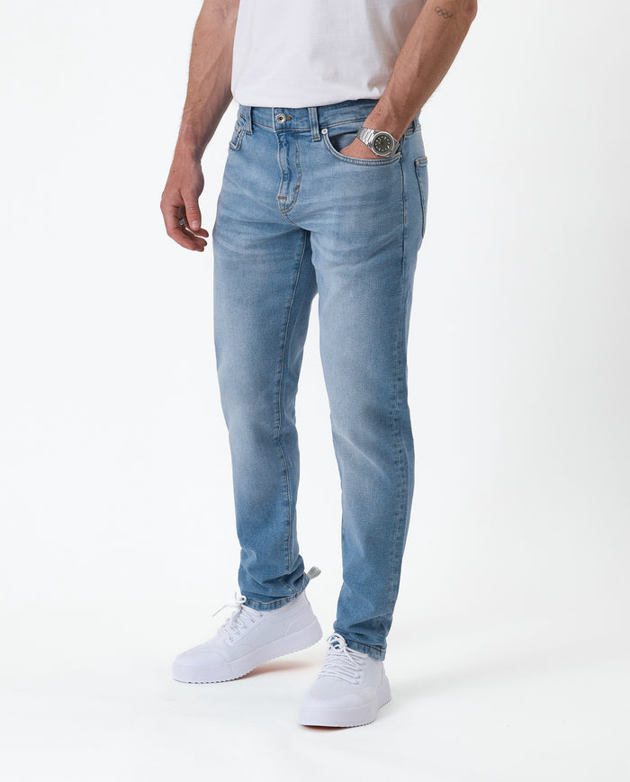 The Jeans Slim Fit in light midwash — worn with white sneakers