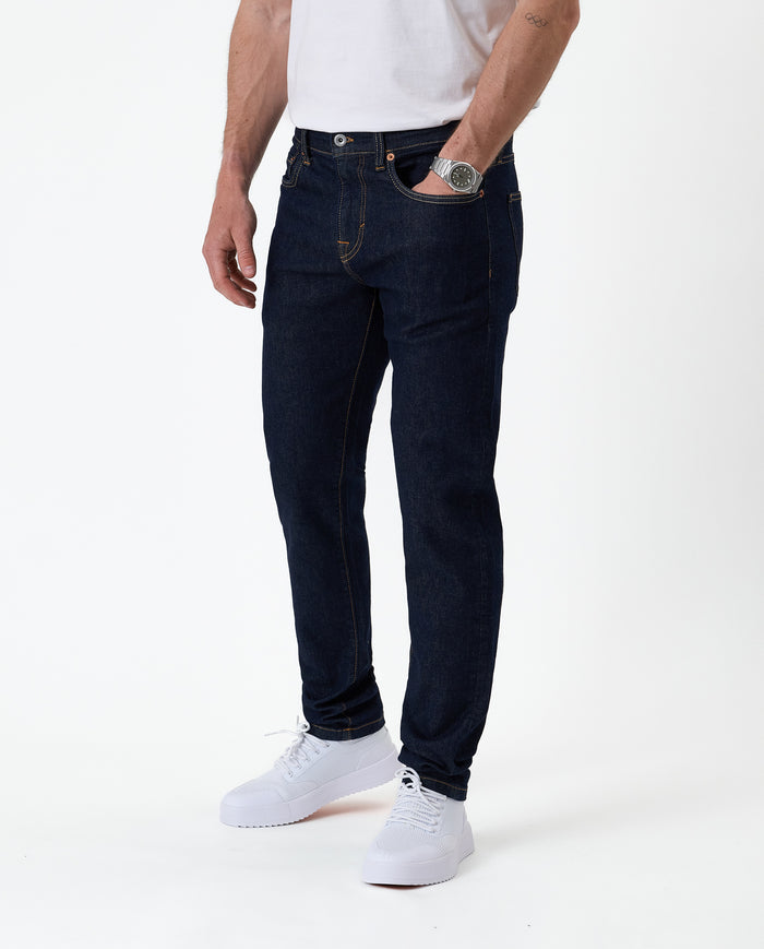 The Jeans Slim Fit in Rinse Wash — front view worn with white sneakers