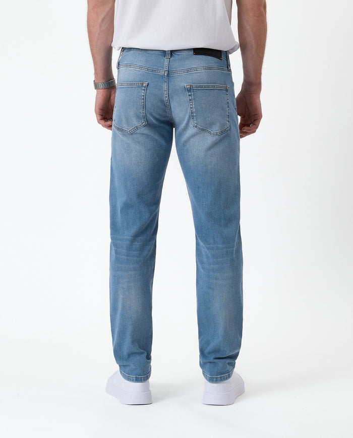 The Jeans Slim Fit in light midwash — back view with the black C'est normal rubber patch