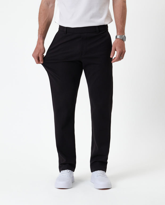 The Proper Pant Regular Fit in black — hand pulling the fabric to show its stretch