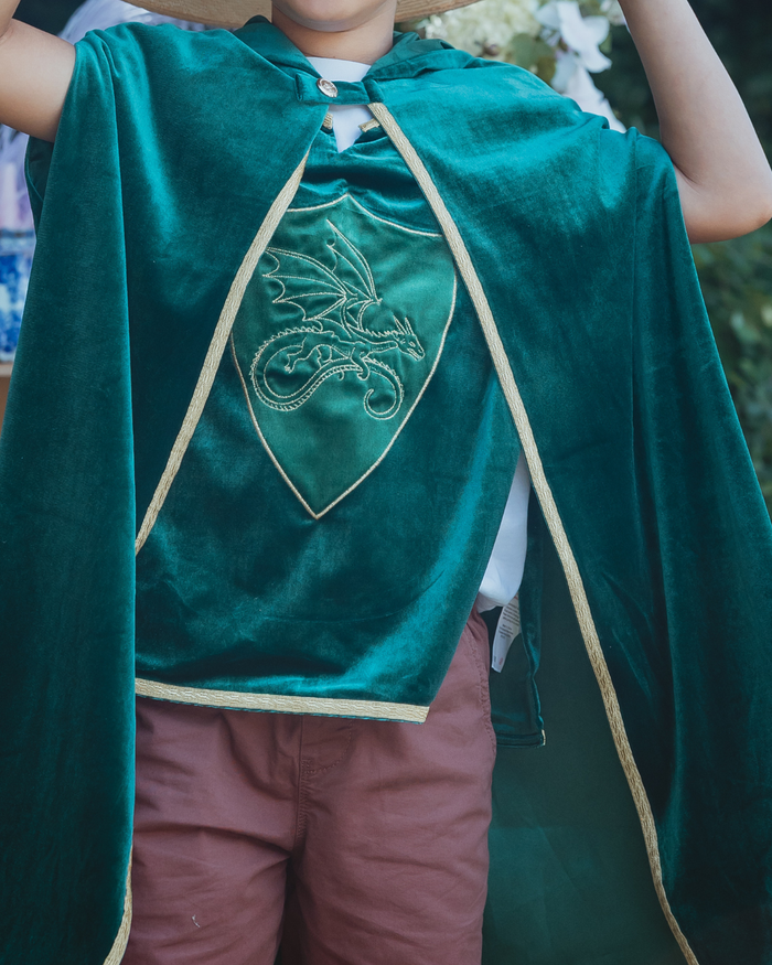 Child wearing a green velvet knight's tabard with an embroidered dragon