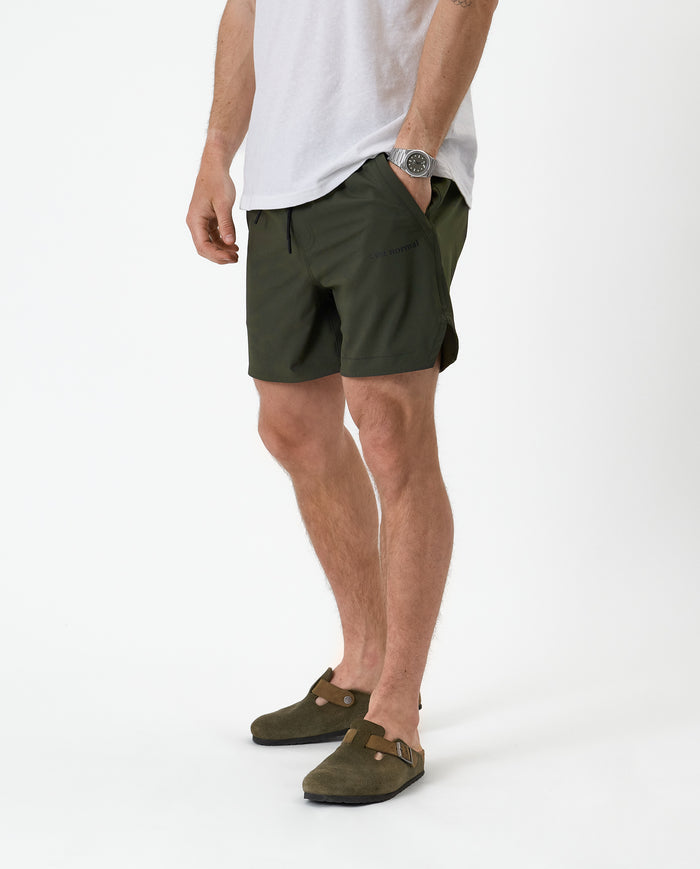 The Shorts in khaki — front view showing the side logo and hand in pocket