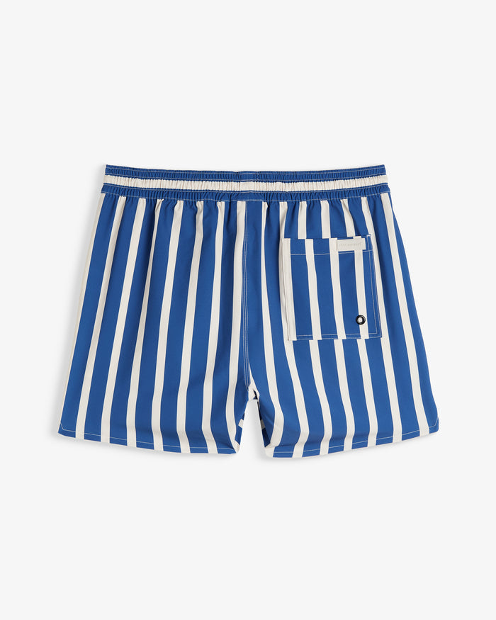 A back view of The Shorts in a blue and white nautical stripe pattern, laid flat on a white background. The image highlights the elasticated waistband, a single back pocket, and a small c'est normal logo patch.